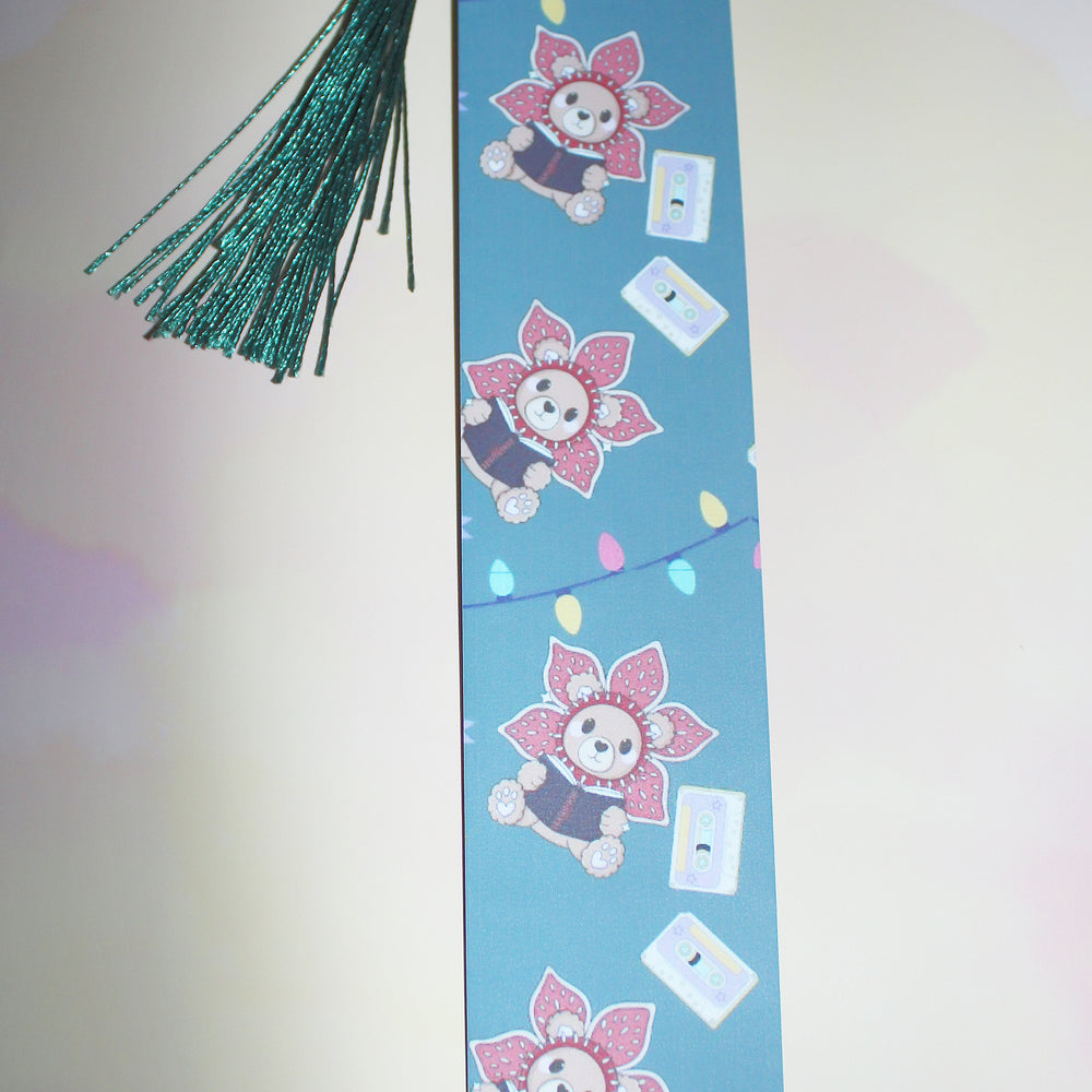 Decorative bookmark with cartoon character and tassels on a light pink background