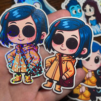 Load image into Gallery viewer, Cartoon character stickers with blue hair and a yellow coat held in a hand.
