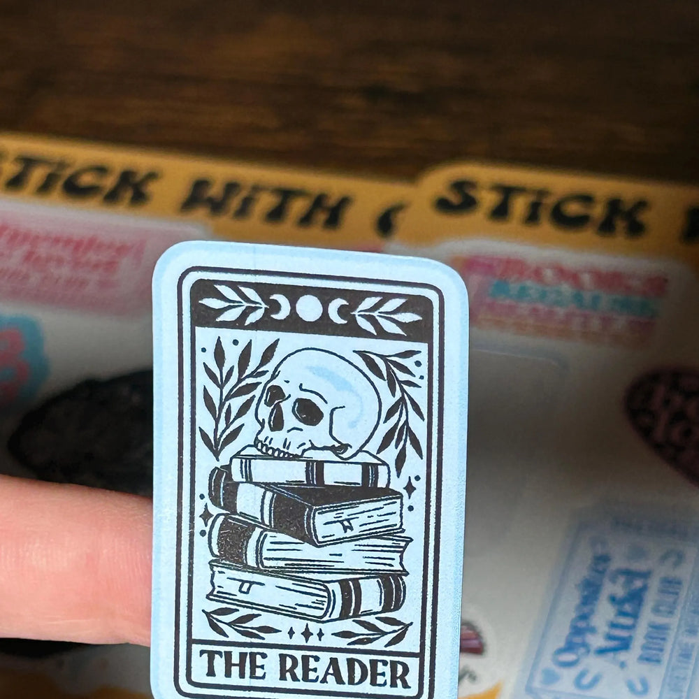 Card with 'The Reader' design held over a box of stickers.