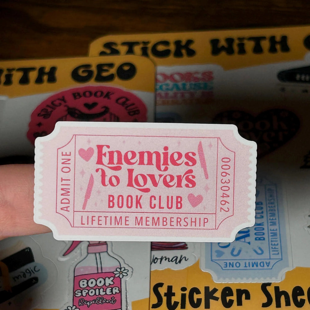 Sticker with 'Enemies to Lovers Book Club' text held over a 'Sticker Sheet' background