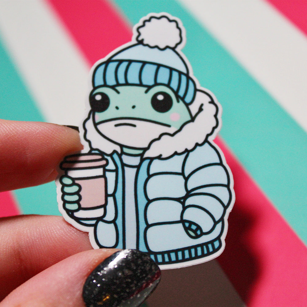 Cute Winter Frog Blue Coat Sticker – Cozy Frog in Puffer Jacket – Frog with Hot Drink – Glossy Waterproof Vinyl Sticker – Pastel Winter Aesthetic – 3.64cm x 5.5cm