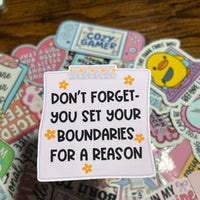Load image into Gallery viewer, Stack of colourful stickers with motivational text on the main Sticker, Yellow Flowers around the text on the purple Sticker. On a wooden surface

