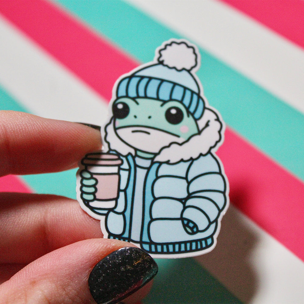 Cute Winter Frog Blue Coat Sticker – Cozy Frog in Puffer Jacket – Frog with Hot Drink – Glossy Waterproof Vinyl Sticker – Pastel Winter Aesthetic – 3.64cm x 5.5cm