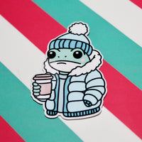 Load image into Gallery viewer, Cute Winter Frog Blue Coat Sticker – Cozy Frog in Puffer Jacket – Frog with Hot Drink – Glossy Waterproof Vinyl Sticker – Pastel Winter Aesthetic – 3.64cm x 5.5cm
