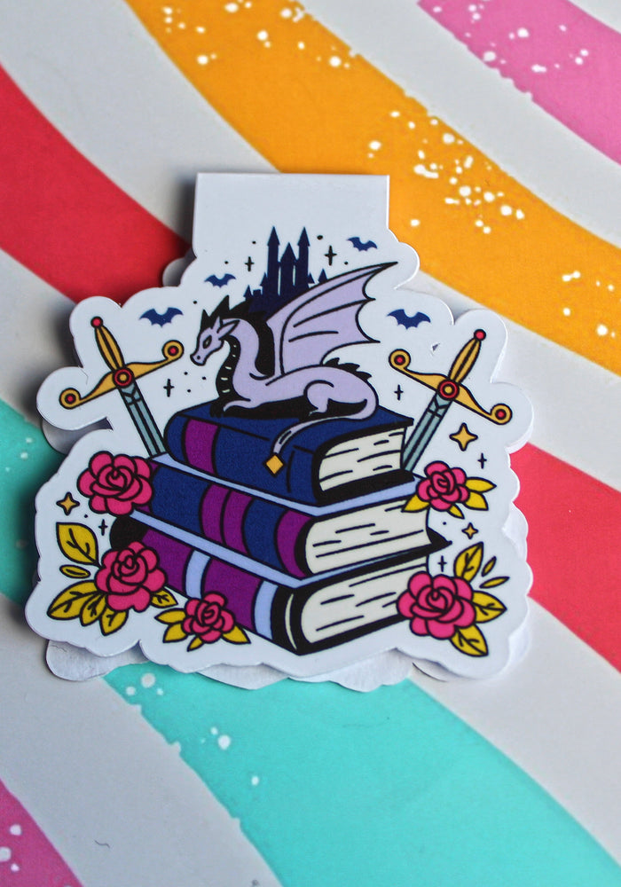 Magnetic Bookmark with a dragon on books against a colourful striped background