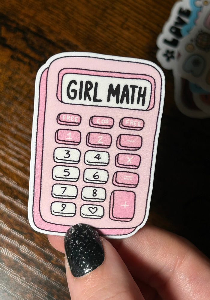 Sticker of a pink calculator with 'Girl Math' text held by a hand on a wooden surface.