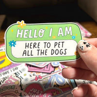 Load image into Gallery viewer, Hand holding a colorful sign with text 'HELLO I AM HERE TO PET ALL THE DOGS' against a blurred background.
