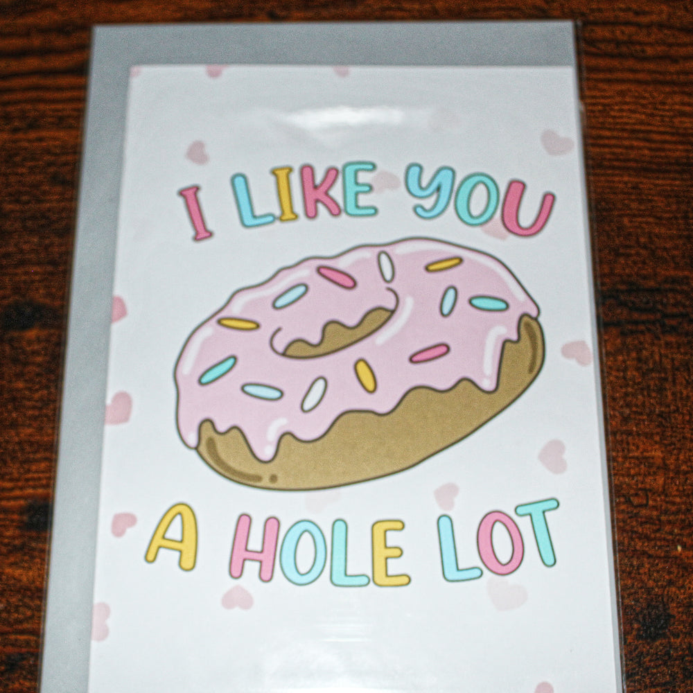 Card with a donut illustration and text 'I like you a hole lot' on a wooden surface