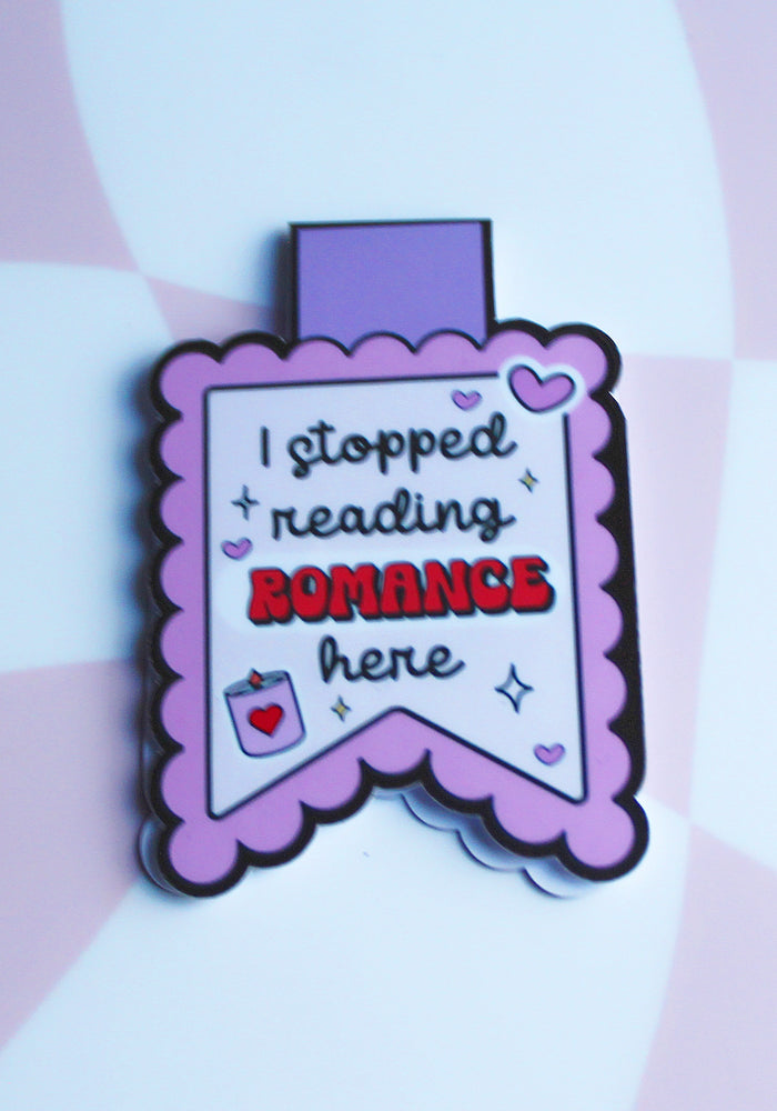 Enamel pin with text 'I stopped reading romance here' on a striped background