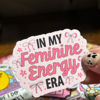 Load image into Gallery viewer, Sticker with 'In My Feminine Energy Era' text held by a hand on a colorful background
