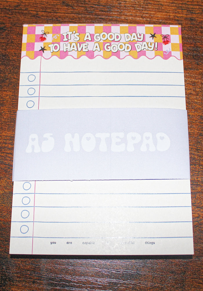 Notepad with motivational quote on a wooden surface