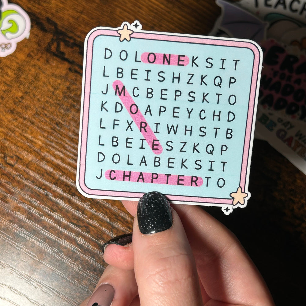 Hand holding a word search sticker with letters on a wooden surface