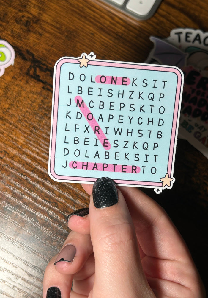 Hand holding a word search sticker with letters on a wooden surface