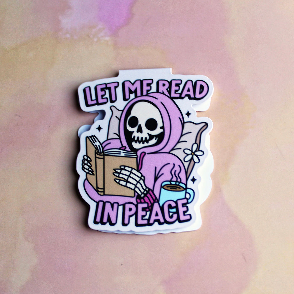 bookmark with a skeleton reading a book and a cup of coffee, text 'Let me read in peace', on a pastel background.