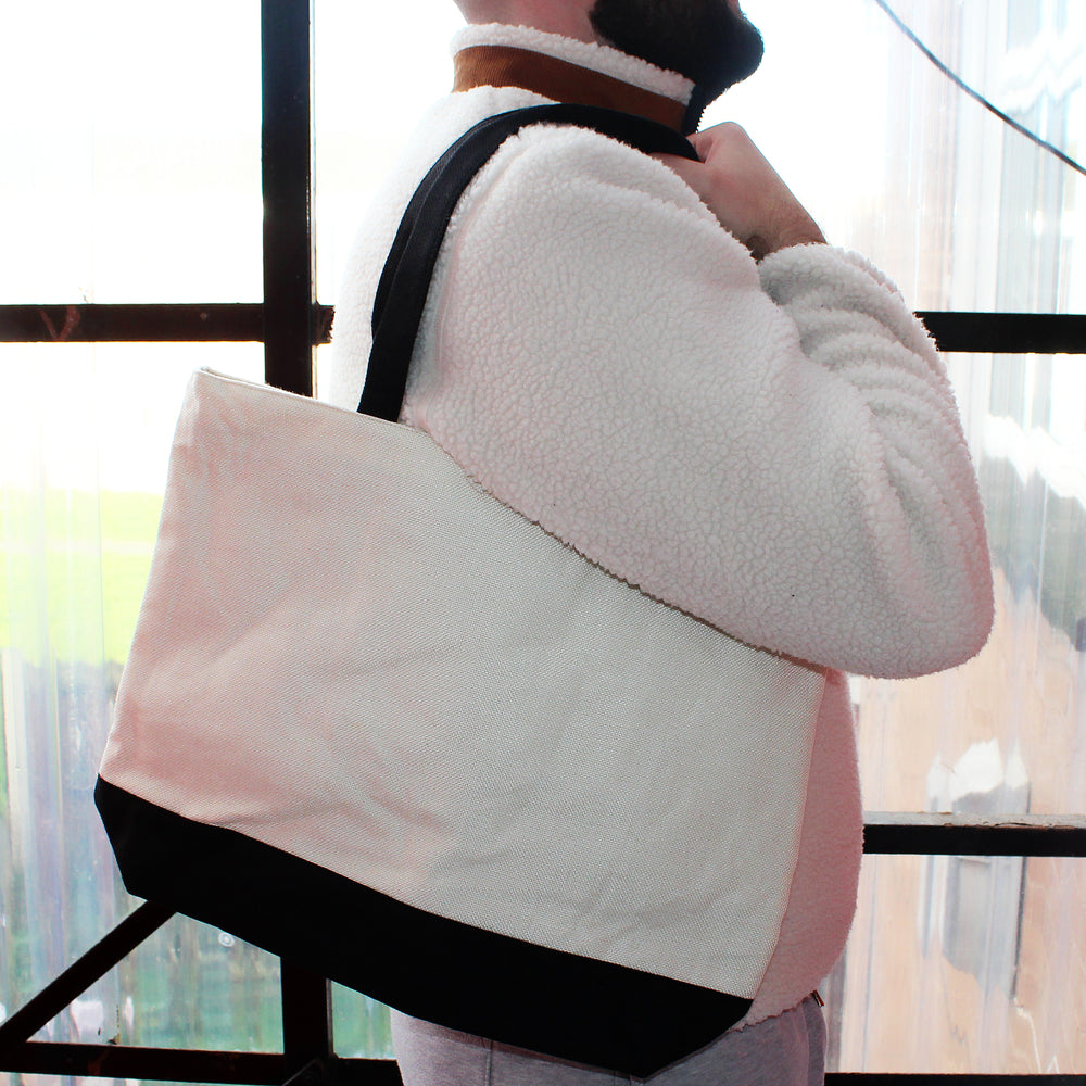 Person wearing a white and jacket with a black strap over their shoulder, standing indoors.