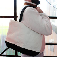 Load image into Gallery viewer, Person wearing a white and jacket with a black strap over their shoulder, standing indoors.

