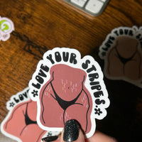 Load image into Gallery viewer, Sticker with 'Love Your Stripes' text held by a hand with black nail polish on a wooden surface.
