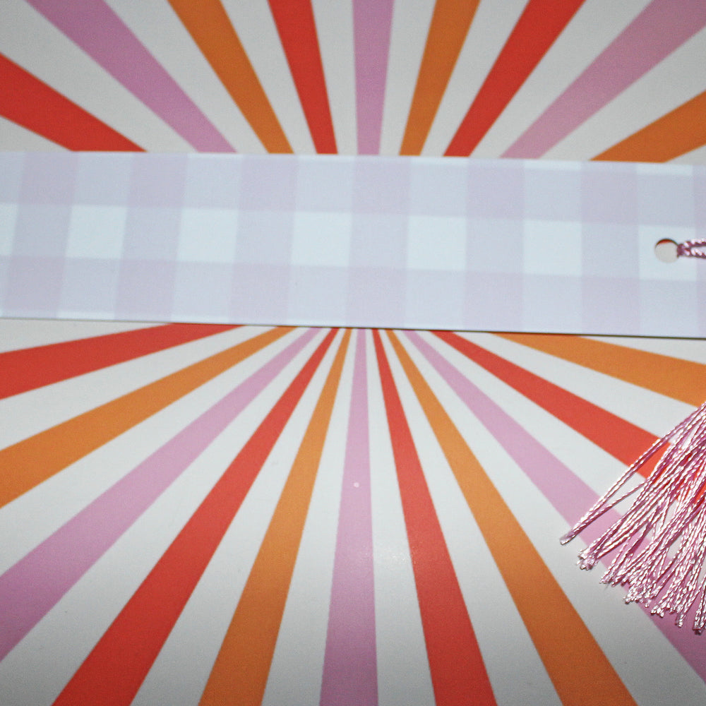 White bookmark with pink tassel on a colorful radial background