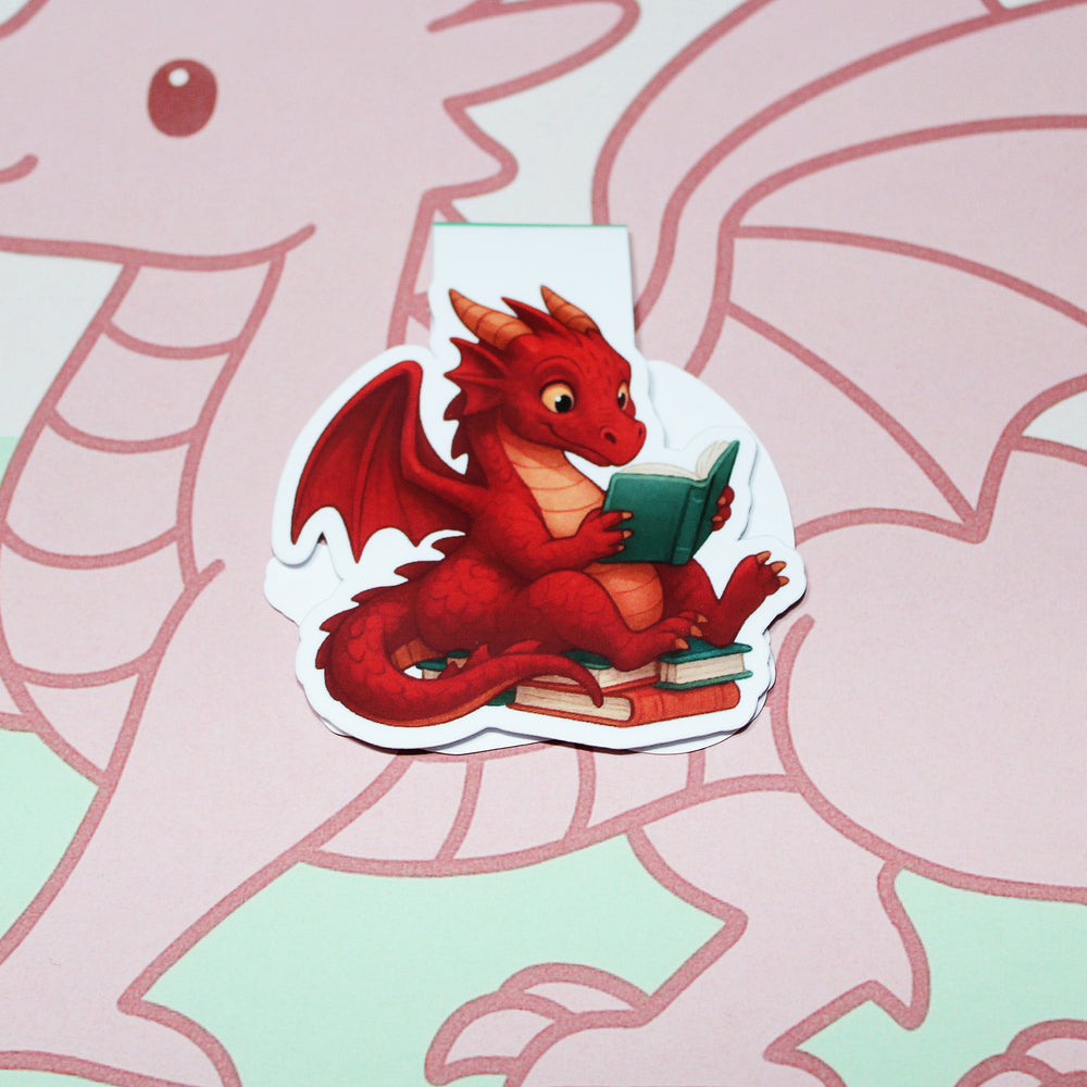 bookmark of a red dragon reading a book on a pink and green background