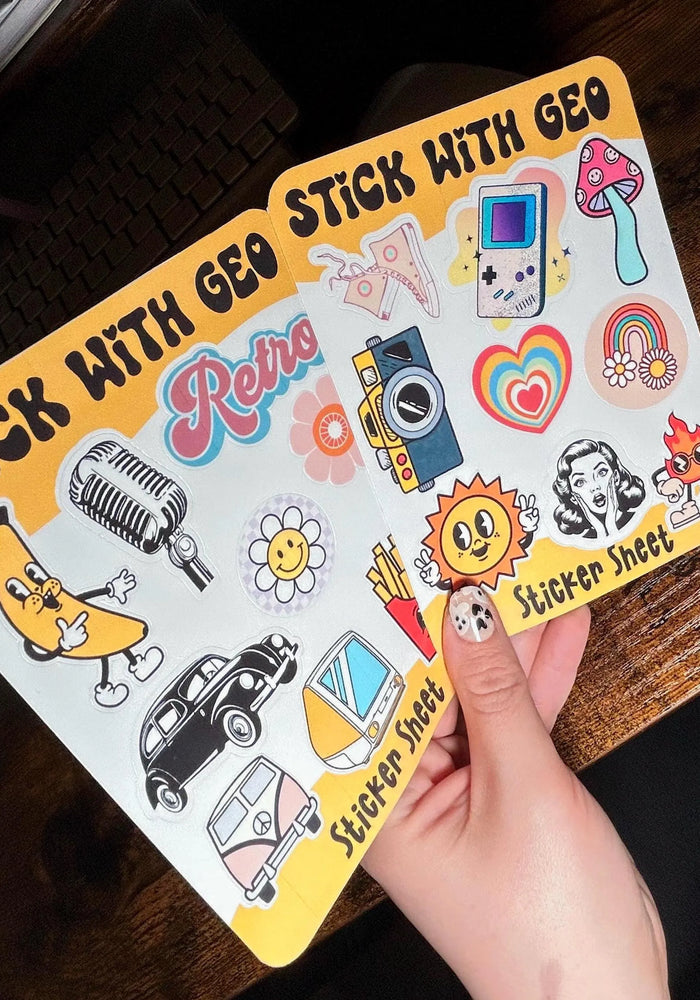 Sticker sheet with various retro-themed stickers held by a hand on a wooden surface.