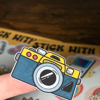 Load image into Gallery viewer, Sticker of a camera held over a colourful background of Sticker Sheets
