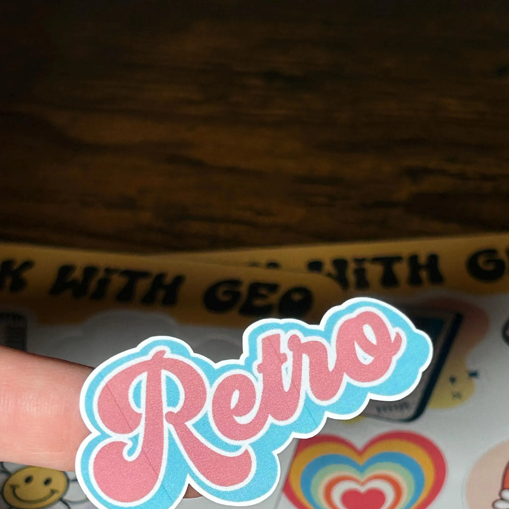 Sticker with 'Retro' text on a wooden surface with other stickers.