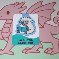 Load image into Gallery viewer, Magnetic bookmark with cartoon sheep reading a book, held by a pink dragon on a light green background
