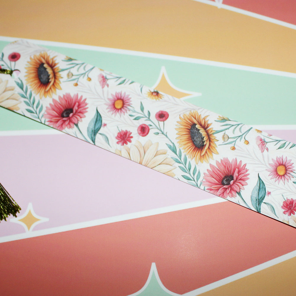 Floral bookmark with a tassel on a colorful striped background