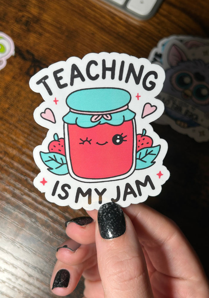 text 'Teaching is my Jam' With a cartoon jam jar with a winking face on it. held by a wooden table