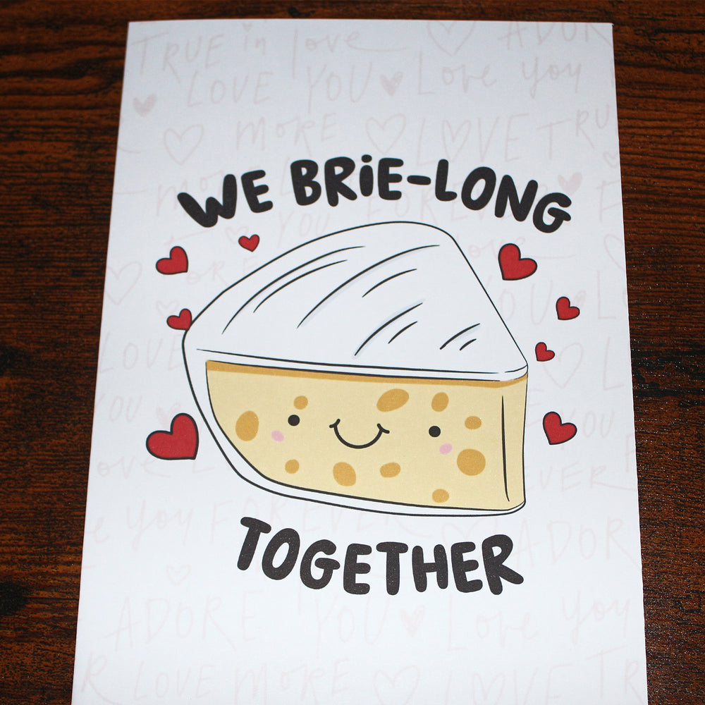 Cartoon brie cheese with hearts and text 'We brie-long together' on a white background.