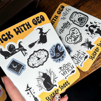 Load image into Gallery viewer, Two sticker sheets with witch-themed designs on a wooden surface.
