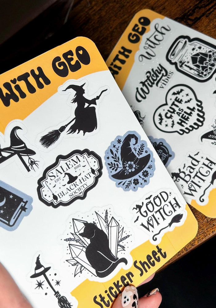 Two sticker sheets with witch-themed designs on a wooden surface.