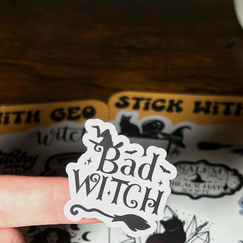 Sticker with 'Bad Witch' text held over a sheet of stickers with similar designs.