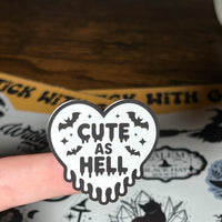 Load image into Gallery viewer, Heart-shaped sticker with 'Cute as Hell' text held over a sticker sheet with various designs.
