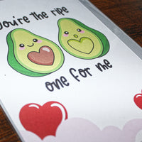 Load image into Gallery viewer, Card with cartoon avocados and hearts on a wooden surface
