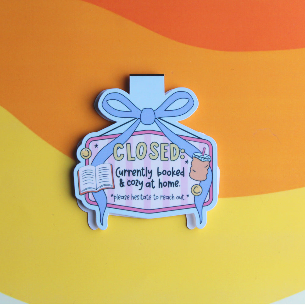 Decorative magnetic bookmark with text 'CLOSED: Currently booked & cozy at home' on a colourful background