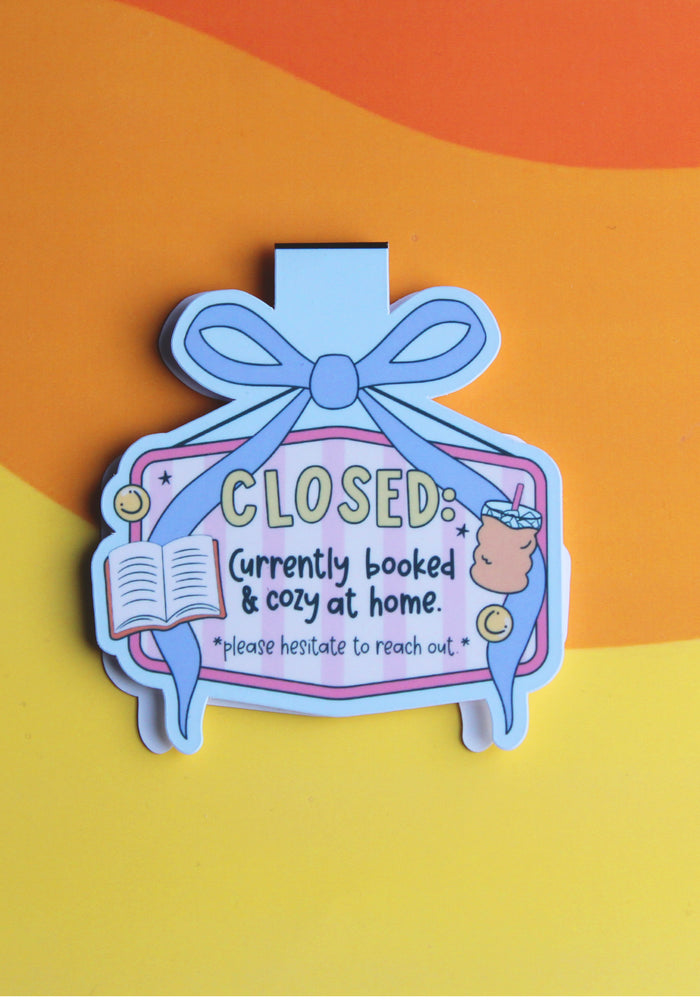 Decorative magnetic bookmark with text 'CLOSED: Currently booked & cozy at home' on a colourful background