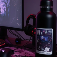Load image into Gallery viewer, A matte black insulated water bottle with a custom graphic label reading 'The Harlot Gamer' sits on a wooden desk next to a computer mouse, mouse pad, and headphones in a dimly lit gaming setup.
