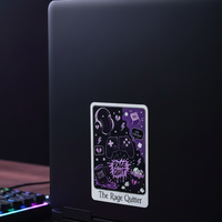 Load image into Gallery viewer, A rectangular desk sticker featuring a tarot card design labeled 'The Rage Quitter' is shown on the back of a black laptop. The scene is set on a wooden desk with a gaming keyboard, mouse, and mousepad under soft, ambient lighting.
