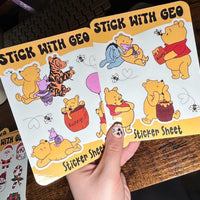 Load image into Gallery viewer, Sticker sheet with cartoon characters held by a hand on a wooden surface
