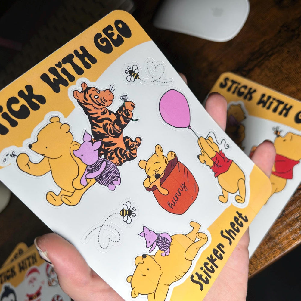 Sticker sheet with cartoon characters held by a hand on a wooden surface