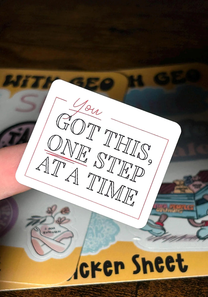 Card with motivational text 'You got this, one step at a time' held over a colorful background.